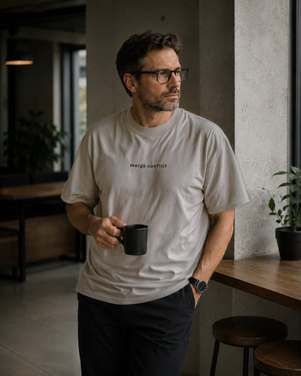 Male model wearing the Shevelo Merge conflict heavyweight oversized tee in Faded Bone.