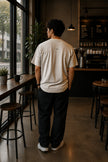 Rear view of the Shevelo Merge conflict heavyweight oversized tee in Faded Bone showing the signature back graphic.