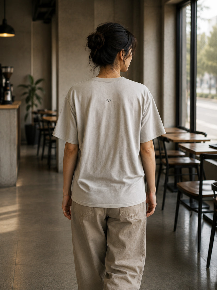 Rear view of the Shevelo Context overflow heavyweight oversized tee in Bone showing the signature back graphic.