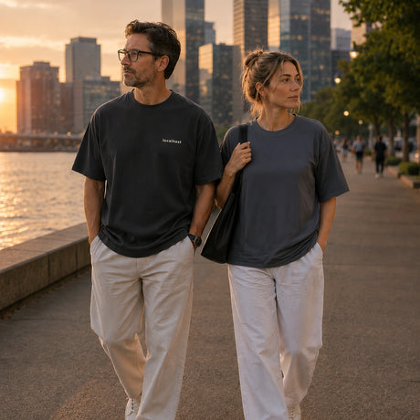 Male model wearing the Shevelo Hot reload oversized tee leisurely walking along the waterway with a colleague.